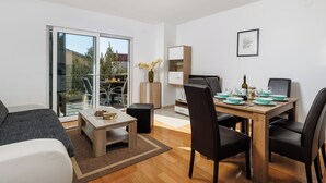 A modern living room with a dining area, large sliding glass doors leading to a balcony, and a view of the outdoors. - Apartment Leko by Interhome (Novi Vinodolski)