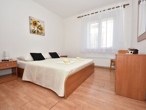 Ein Schlafzimmer mit einem Bett, Nachttischen, einem Schreibtisch und einem Fenster mit Vorhängen.