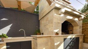 Cocina exterior con estructura de piedra, un lavamanos y dos armarios.