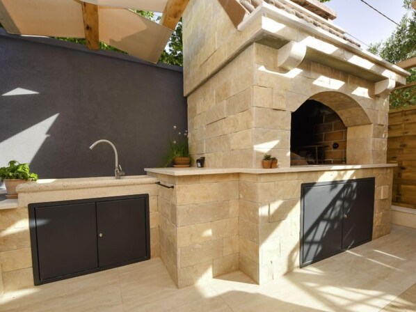 An outdoor kitchen with a stone structure, a sink, and two cabinets.