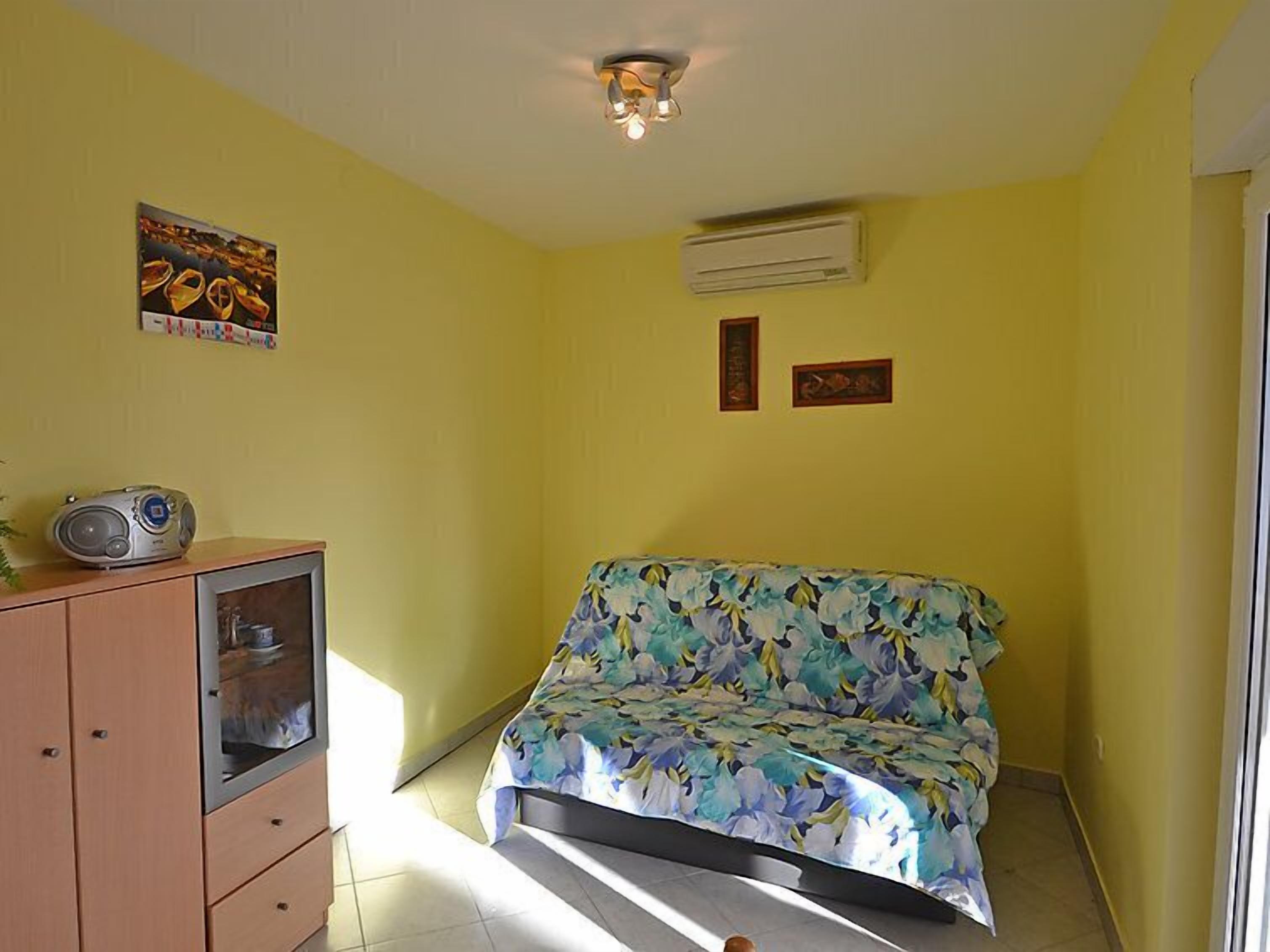 A room with a bed, a cabinet, and an air conditioner.