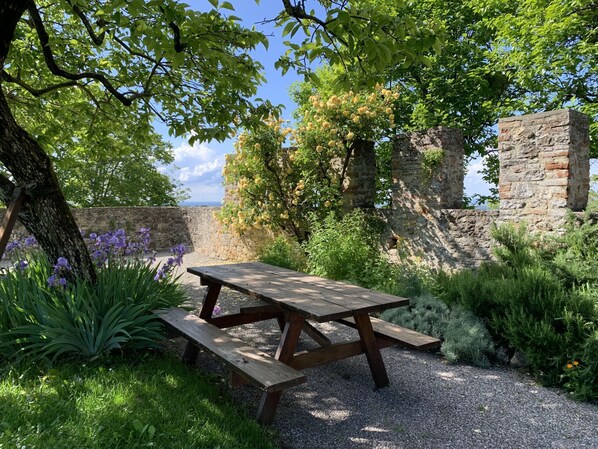 Una mesa de picnic en un jardín con un muro de piedra y árboles.