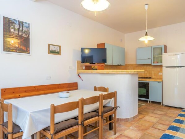 Una cocina compacta con comedor, televisión y refrigerador.
