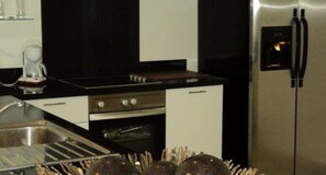 A kitchen with a stainless steel refrigerator, a stove, and a sink.