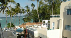 A hotel with a pool area, palm trees, and a view of the ocean.