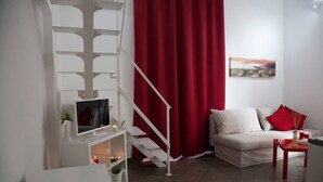 A modern living room with a staircase, a sofa, a TV, and a red curtain.