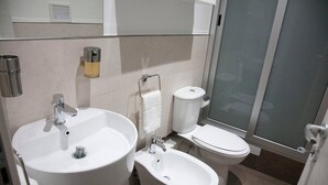 A modern bathroom with a sink, bidet, toilet, and a glass shower enclosure.