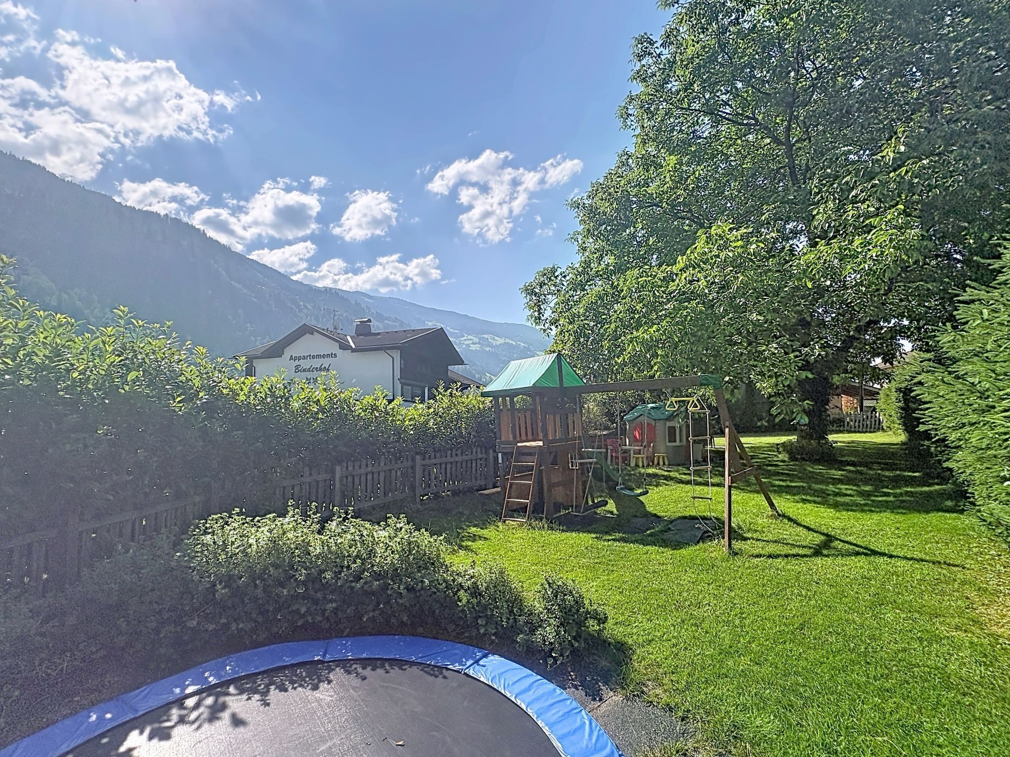 A residential area with a playground, a trampoline, and a building labeled 'Apartments Bladerhof' with a mountain backdrop.