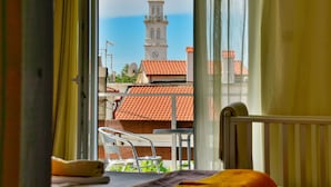 A room with a bed, a chair, and a view of a tower through a window. - Andrijana by Interhome (Novi Vinodolski)
