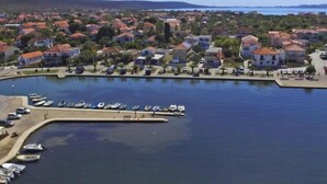 Een kustplaats met een jachthaven, huizen met rode daken en een helder uitzicht op de zee.