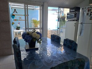 Een eethoek met een glazen tafel, stoelen en een bloevas.