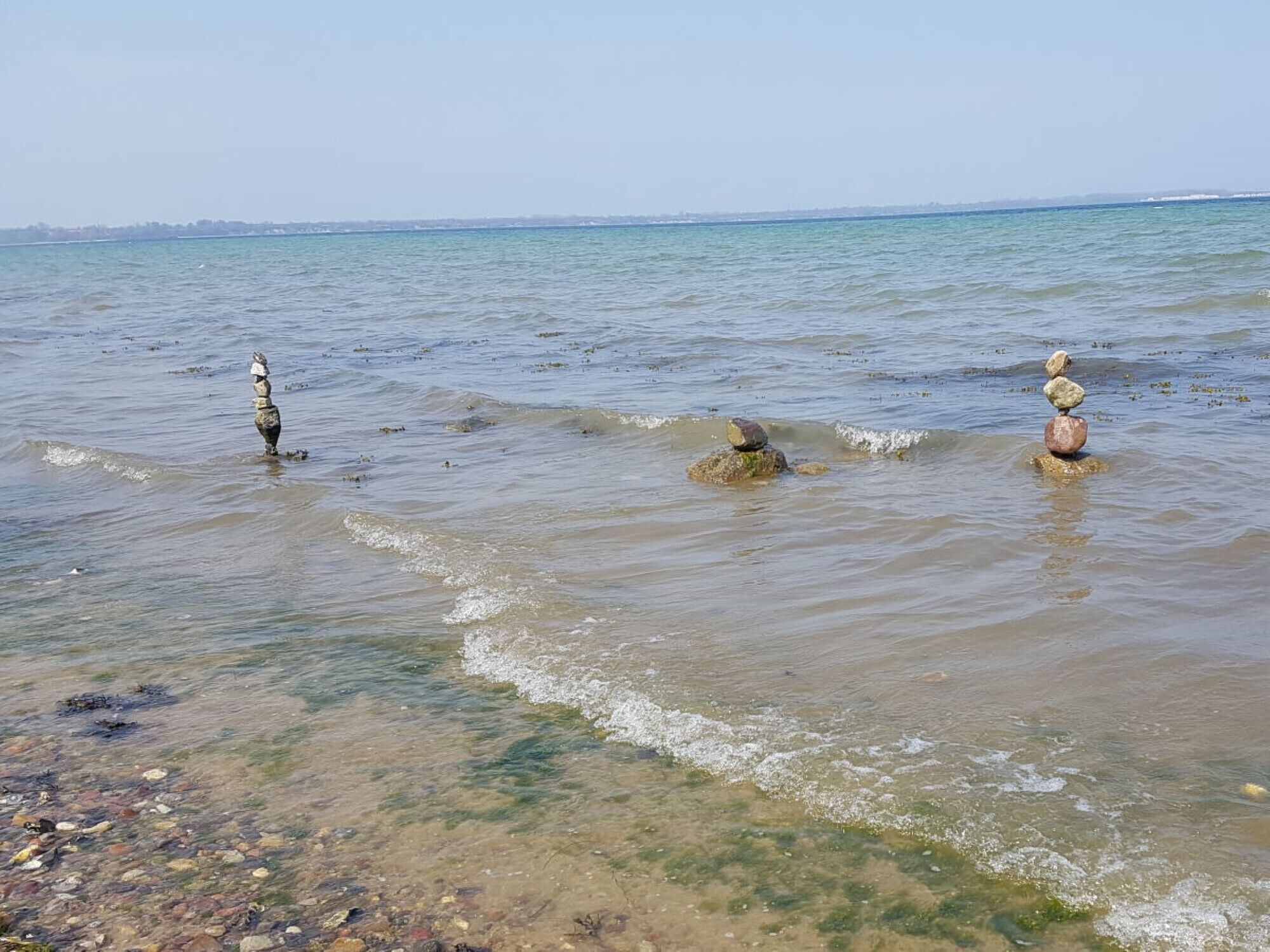 Una playa con aguas claras y poco profundas, y rocas.