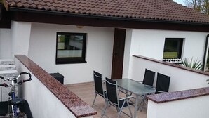 Un patio con una mesa, sillas, una bicicleta y un ventanal.