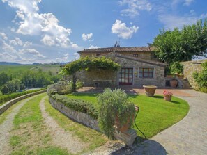 A stone house with a tiled roof, a red door, and a stone wall with a garden. - Locazione turistica Selvapiana by Interhome (Greve in Chianti)
