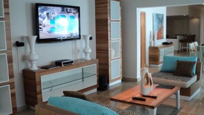 A modern living room with a flat-screen TV, a wooden coffee table, and a sofa.