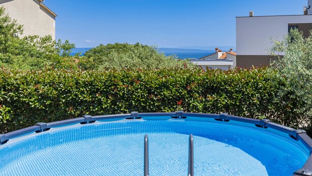 Una piscina con vistas despejadas al mar y edificios al fondo.