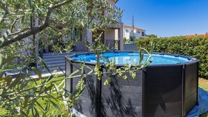 Una piscina rodeada de una terraza de madera, con un edificio al fondo.
