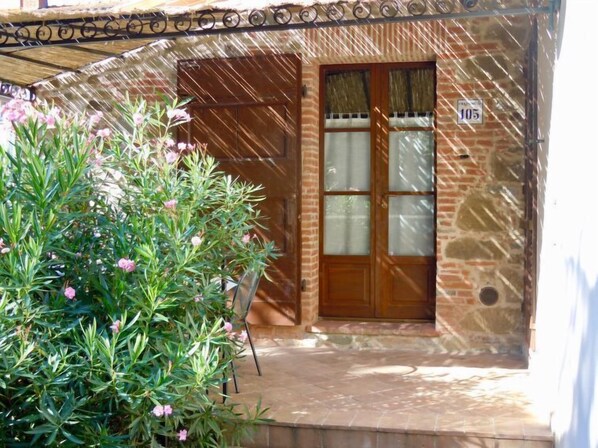 Un edificio de piedra con puerta de madera y ventana de vidrio esmerilado.