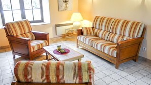 Ein gemütliches Wohnzimmer mit gestreiften Sofas und Sesseln, einem Couchtisch und einer Lampe.