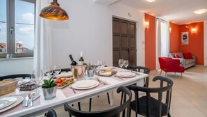 A dining area with a table set for four, a wine bottle, and a potted plant. - Vacation home Amberg by Interhome (Opatija/Kastav)