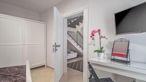A modern bedroom with a bed, a desk, a chair, a TV, a potted orchid, and a staircase leading to a balcony. - Vacation home Amberg by Interhome (Opatija/Kastav)