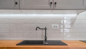 A kitchen with a black sink, white tiled backsplash, and wooden countertop. - Vacation home Amberg by Interhome (Opatija/Kastav)