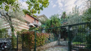 Una zona residencial amurallada con un muro de piedra, una scooter estacionada y un edificio con balcones.