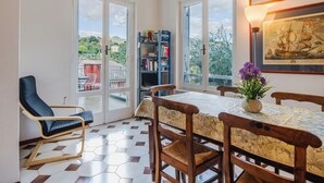 Un comedor con una mesa, sillas, una estantería y vistas al exterior a través de puertas de vidrio.
