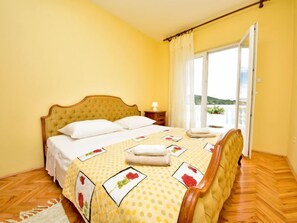 Une chambre à coucher avec un lit, une table de chevet, une fenêtre avec des rideaux et une vue sur l’extérieur.
