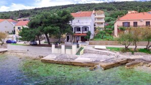 Un pueblo costero con aguas cristalinas, un muelle de piedra y edificios de tejados rojos.