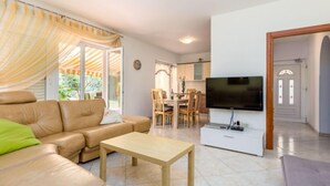 A living room with a sofa, a coffee table, a TV, and a dining area with chairs and a table. - Apartment Silva by Interhome (Fažana/Peroj)