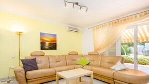 A living room with a beige sectional sofa, a wooden coffee table, and a painting of a sunset. - Apartment Silva by Interhome (Fažana/Peroj)