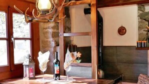 Un bancone di legno rustico con un lampadario, una bottiglia di vino e bicchieri sul ripiano.