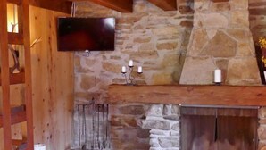 Un camino in pietra con una TV montata sopra, candele e un arredamento in legno rustico.