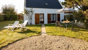 A house with a dark roof, white exterior walls, and a small front porch. There is a patio area with a table and chairs, and a covered outdoor seating area. - Ty Pendruc by Interhome (Tregunc)