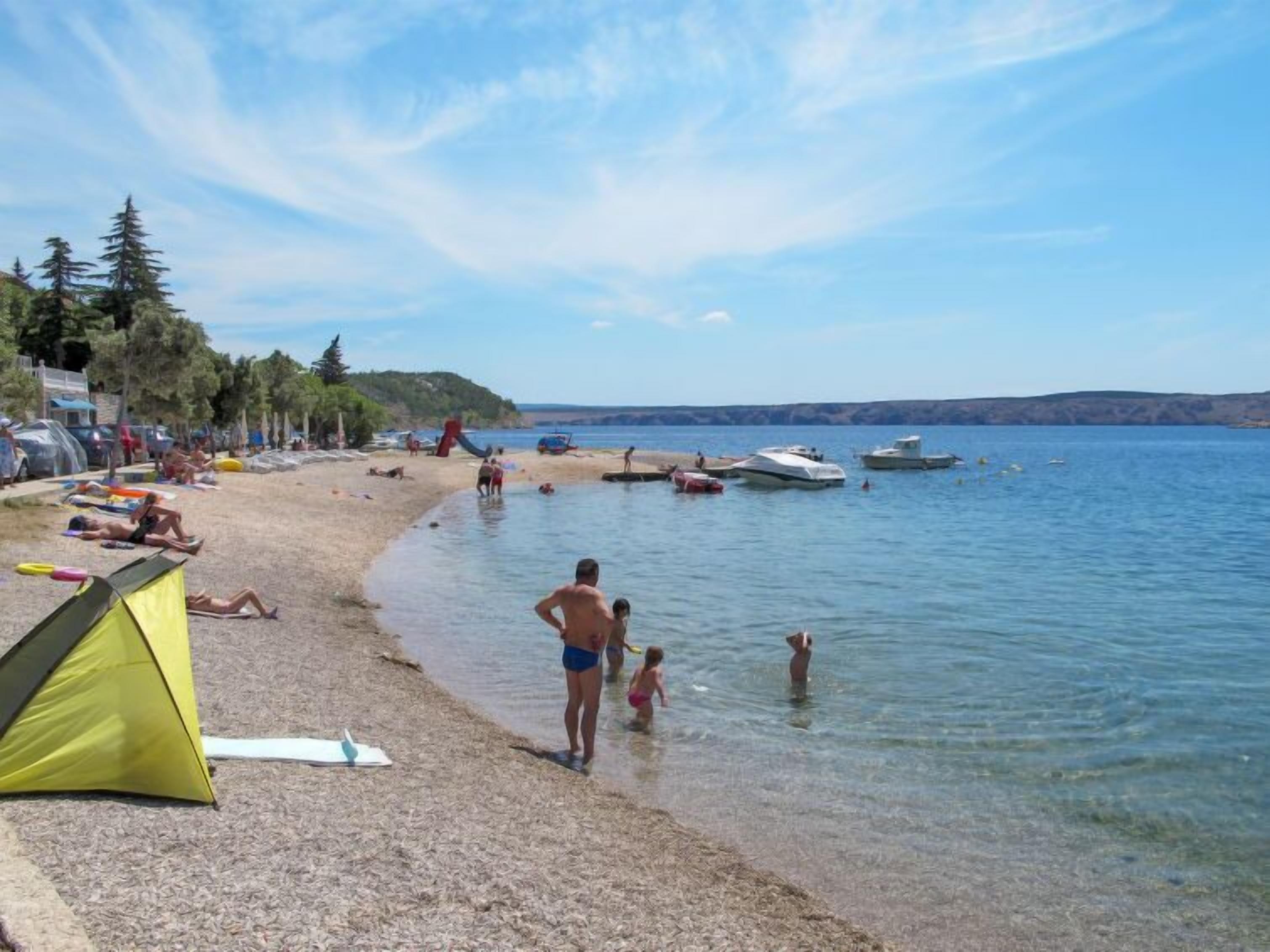 A beach with tents, people, and boats.