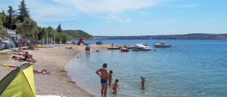 A beach with tents, people, and boats.