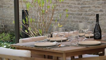 Une table de salle à manger en bois, mise avec des assiettes, des verres et des couverts, accompagnée d’une bouteille de champagne.