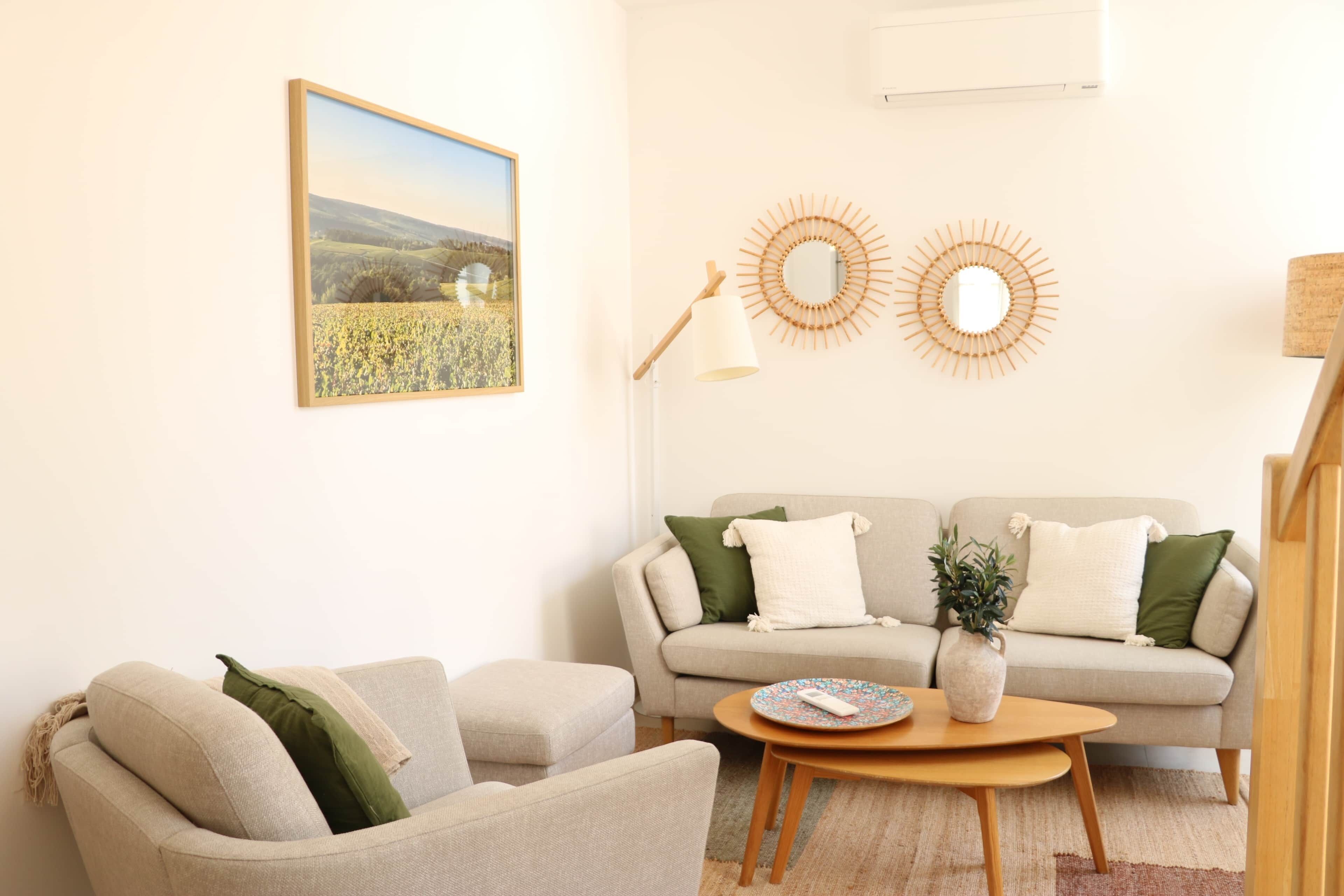 A living room with a sofa, armchairs, a coffee table, and decorative wall mirrors.