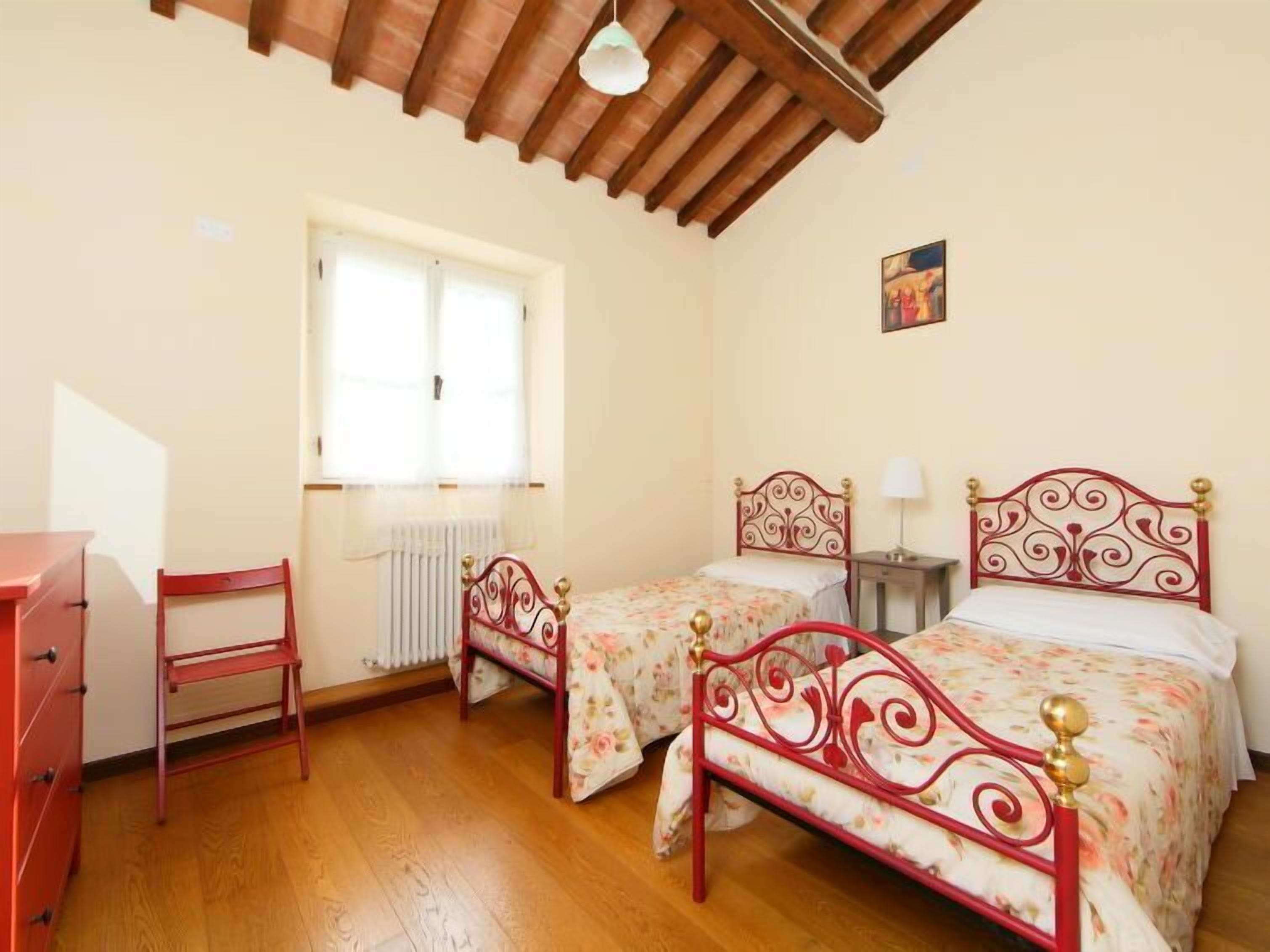 Une chambre avec deux lits, une commode, une fenêtre et un radiateur.