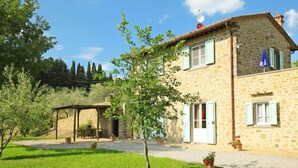 Una casa de piedra con un porche cubierto y un patio césped.