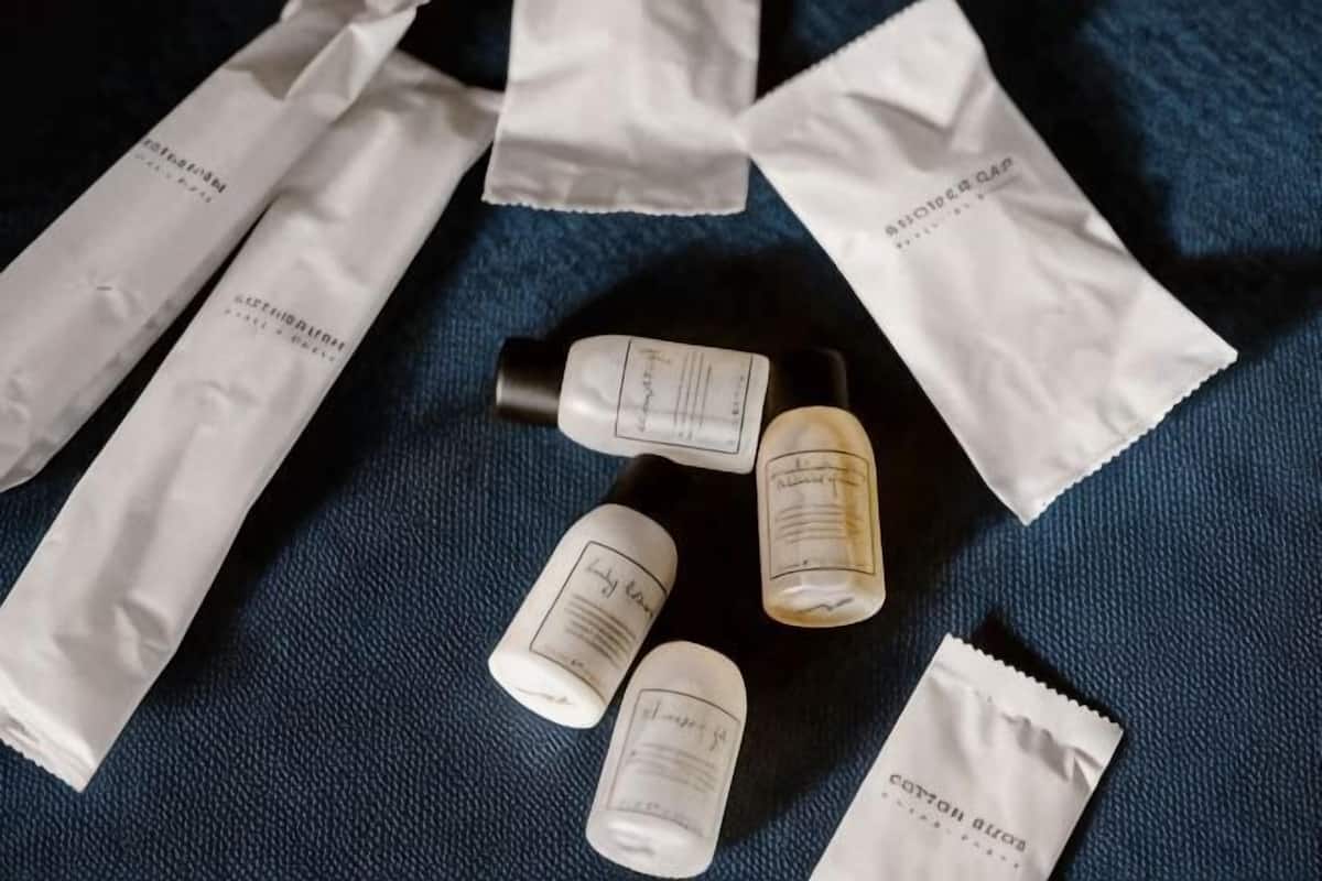 Several white packets and small bottles on a dark fabric surface.
