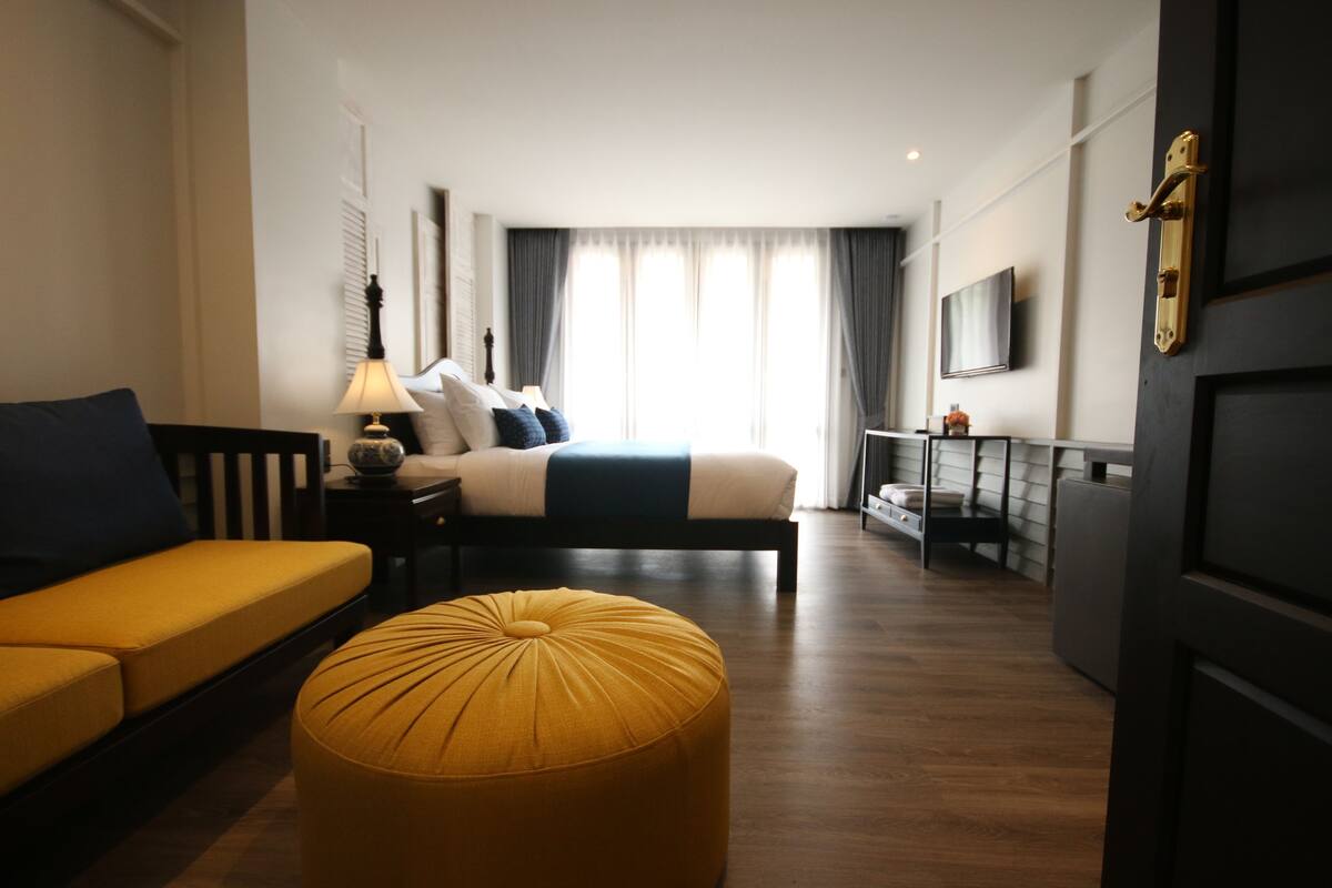Una habitación de hotel con cama, sofá, una mesita y televisor.