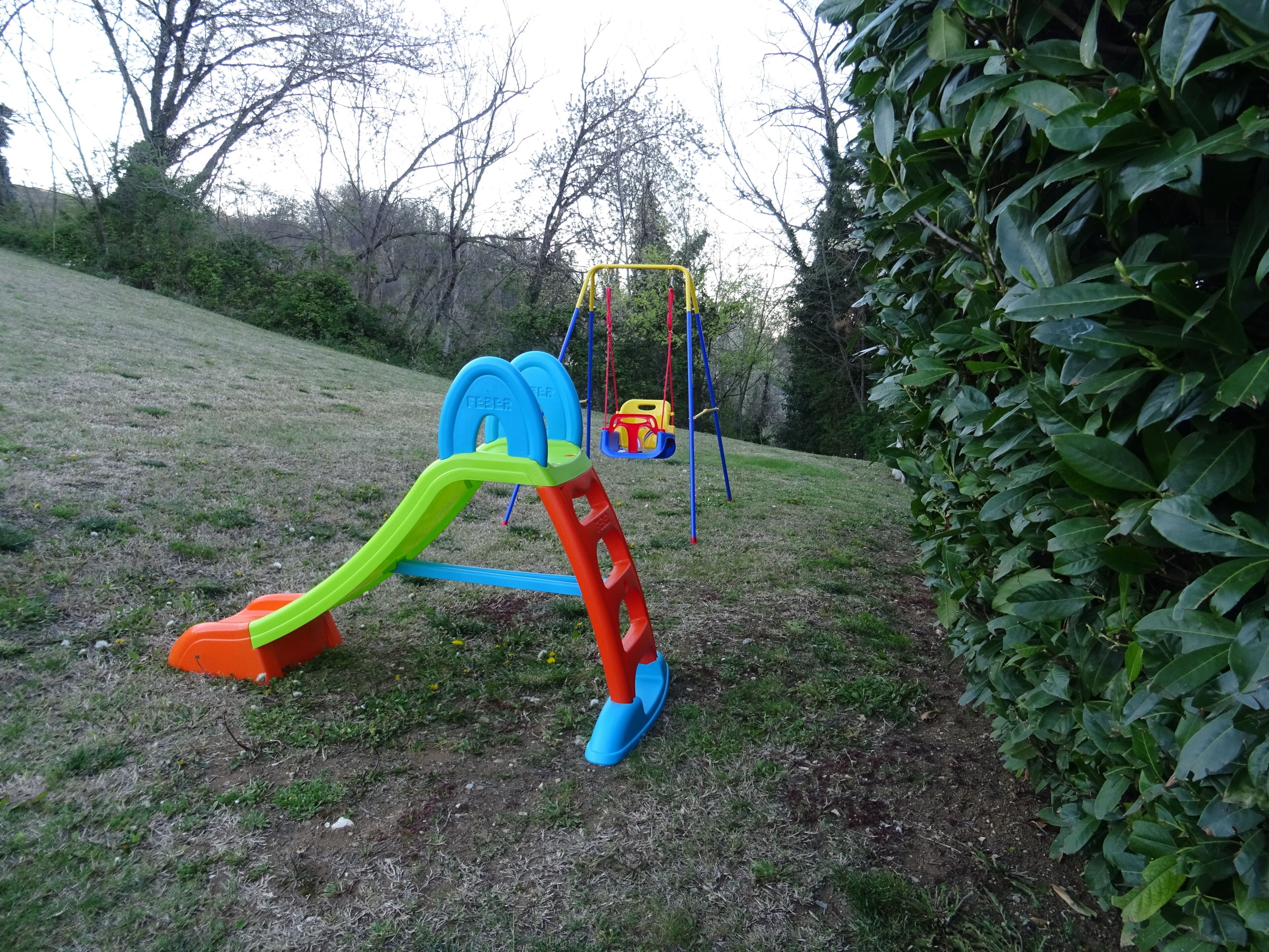 A playground with a slide and swings in a grassy area.
