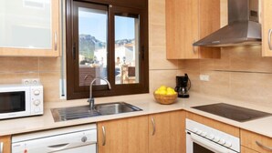 Een moderne keuken met houten kastjes, een ingebouwde kookplaat, een vaatwasser en een raam met uitzicht.