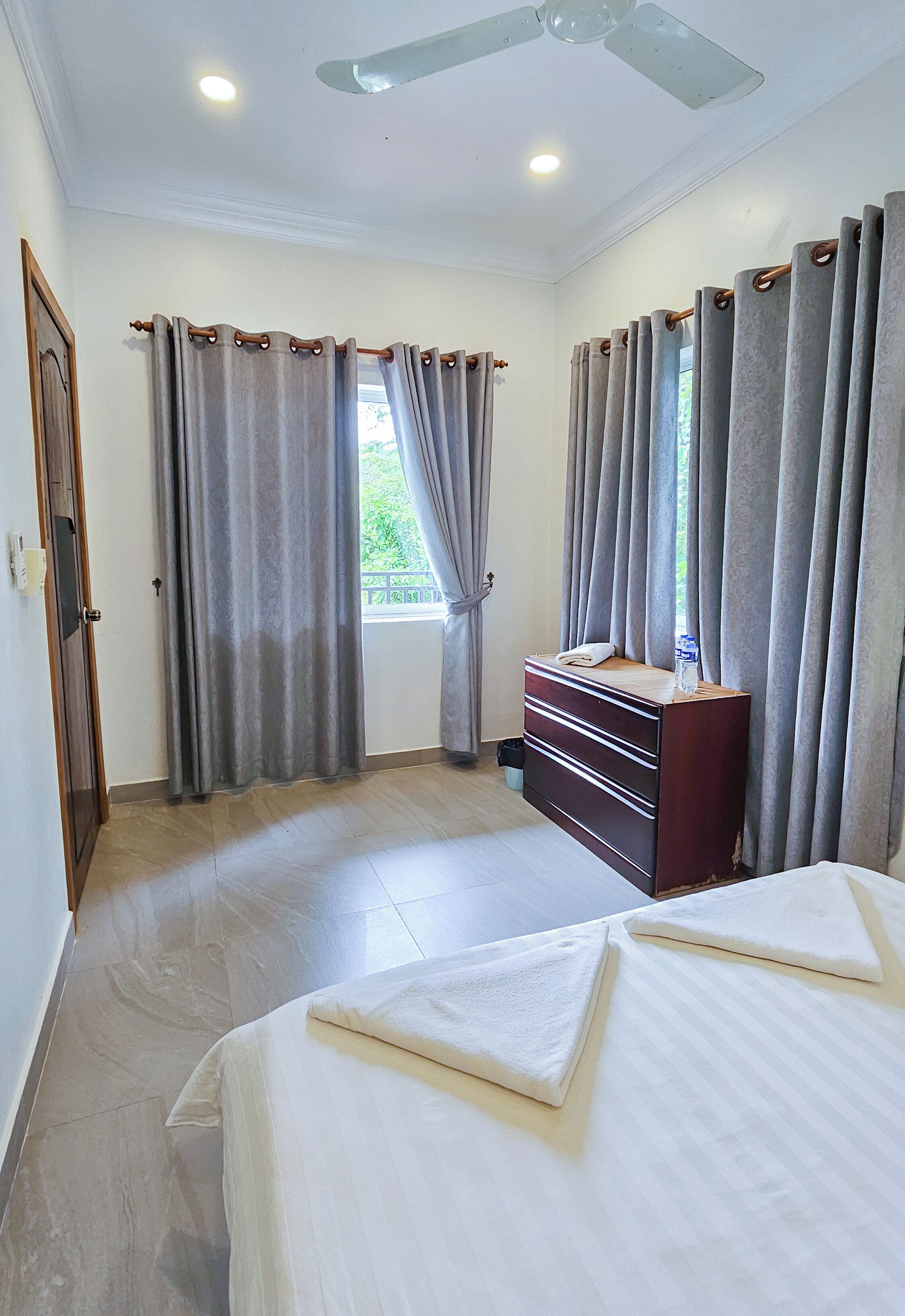 A bedroom with a bed, a dresser, and a ceiling fan.