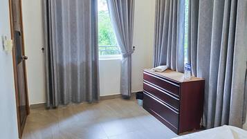 A bedroom with a bed, a dresser, and a ceiling fan.