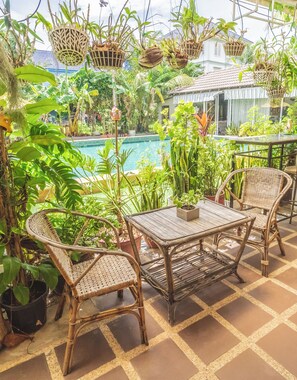 An outdoor patio with wicker furniture, a pool, and various potted plants. - Sanssouci Kep (Kep)