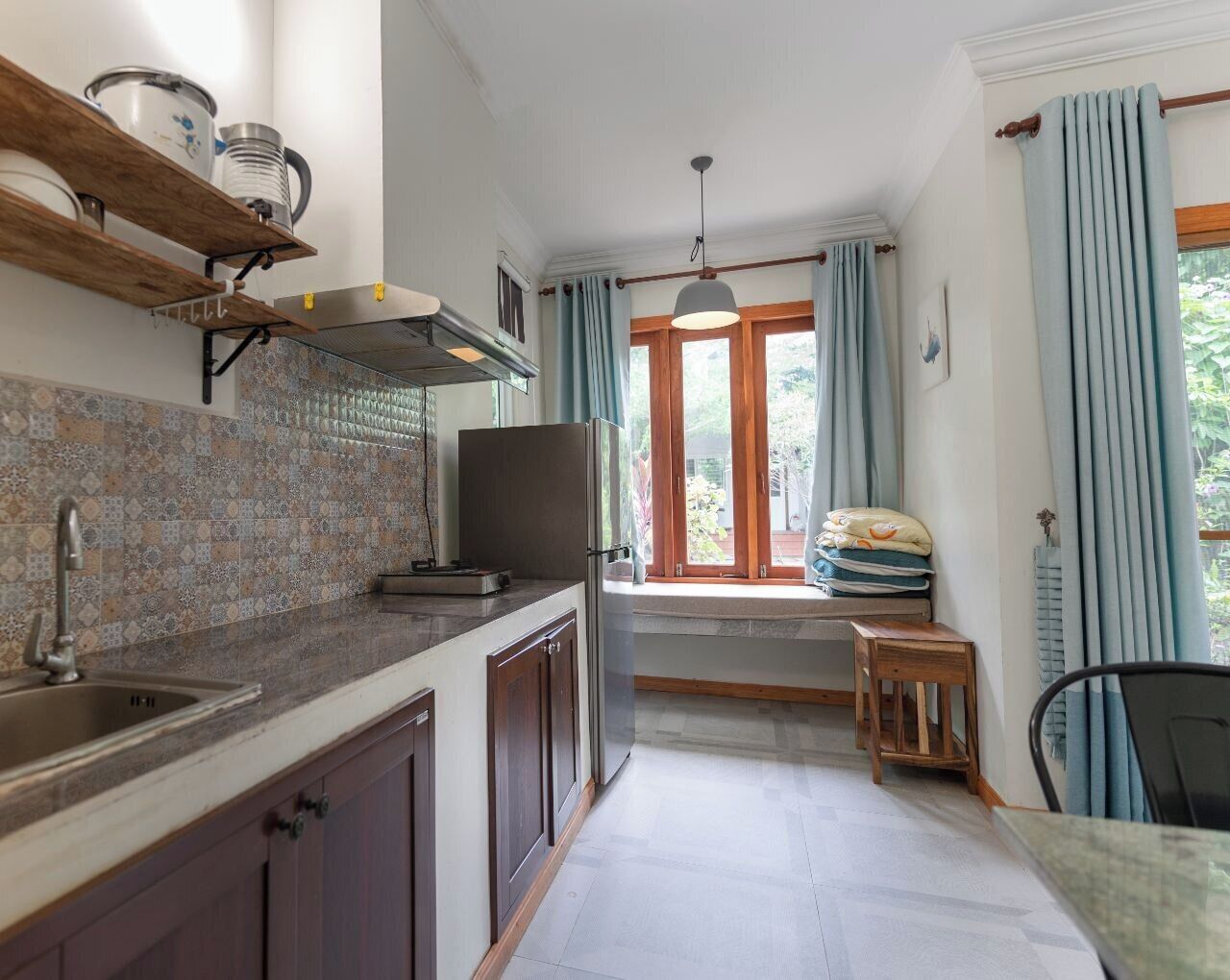 Eine Küche mit gefliestem Rücksprung, Backofen, Spüle und einem Fenster mit Vorhängen.