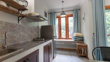 Eine Küche mit gefliestem Rücksprung, Backofen, Spüle und einem Fenster mit Vorhängen.
